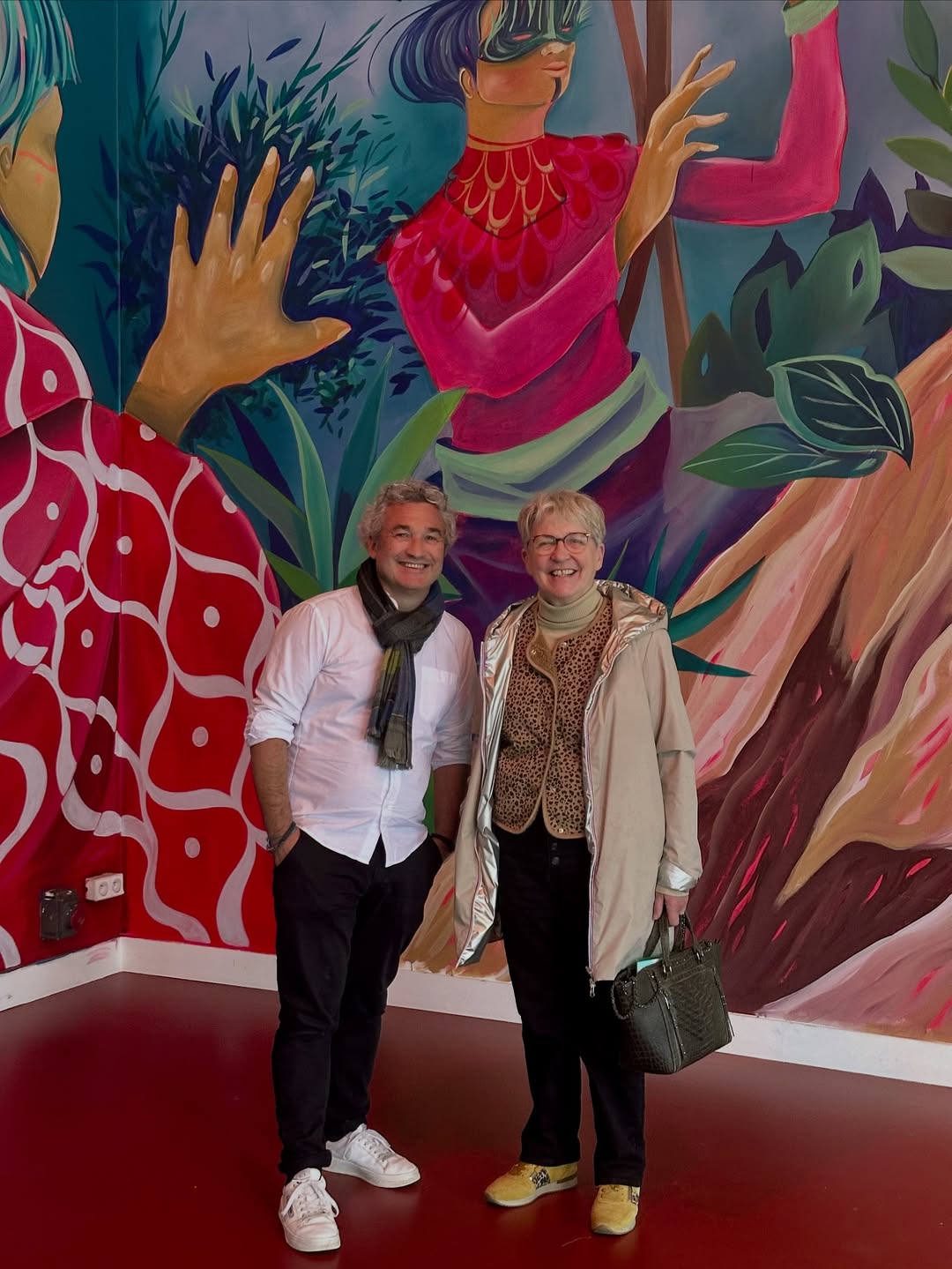 Paulette Matray et Nicolas Royer, souriants, devant une grande fresque colorée à l’Espace des Arts