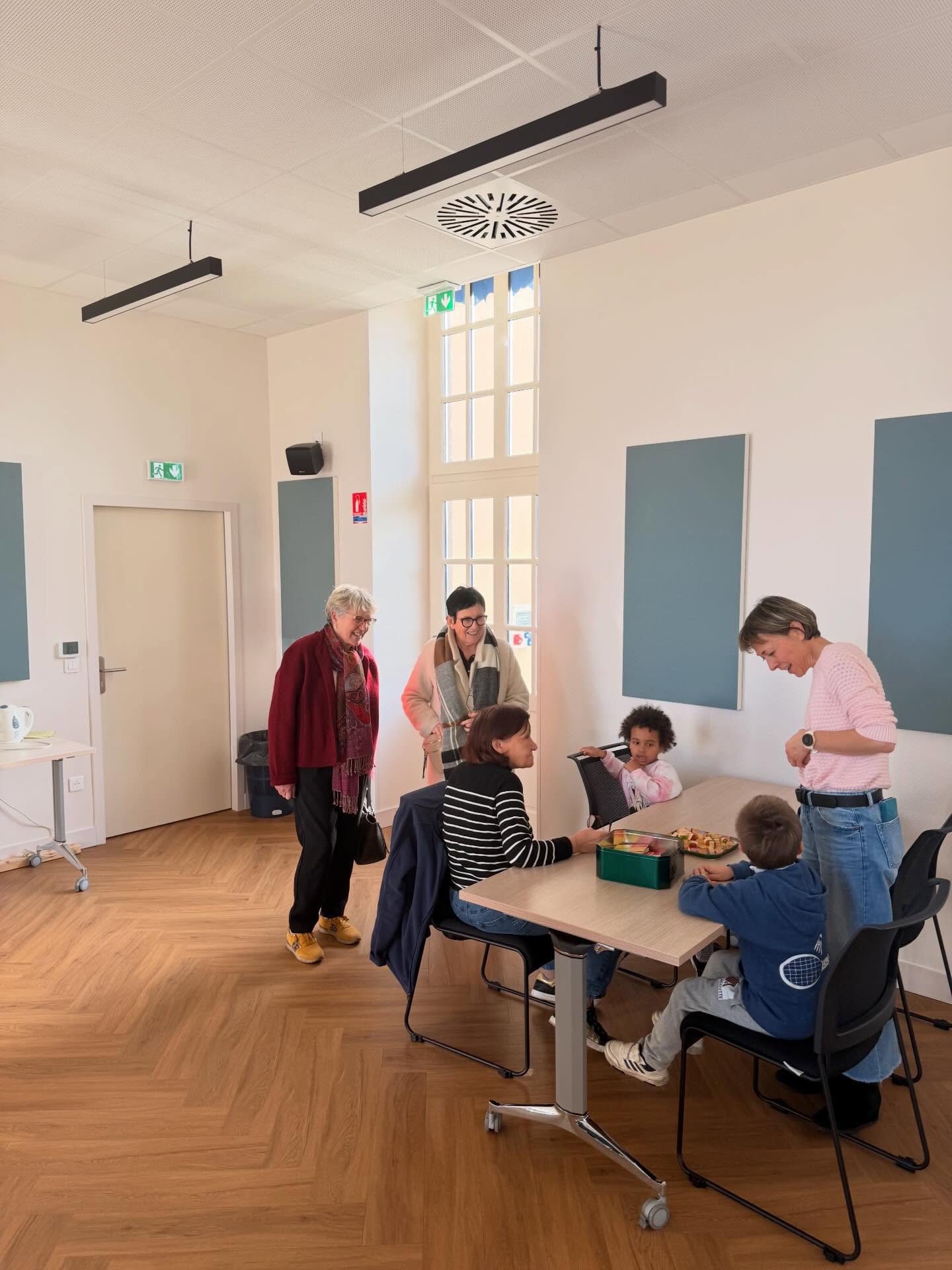 Paulette Matray visite une salle lumineuse où des enfants jouent autour d’une table avec des animatrices, à Bourbon-Lancy