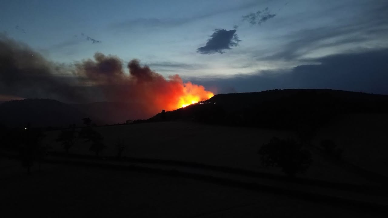 Incendie de nuit dans le Morvan : de hautes flammes orange et un panache de fumée s’élèvent derrière une colline