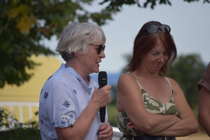 Paulette Matray prend la parole au micro en plein air, aux côtés d’une élue, lors des commémorations de la Libération
